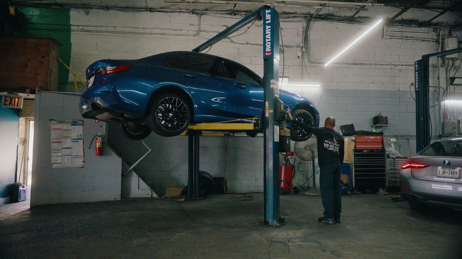 Blue BMW sedan on a Rotary lift with a technician at work