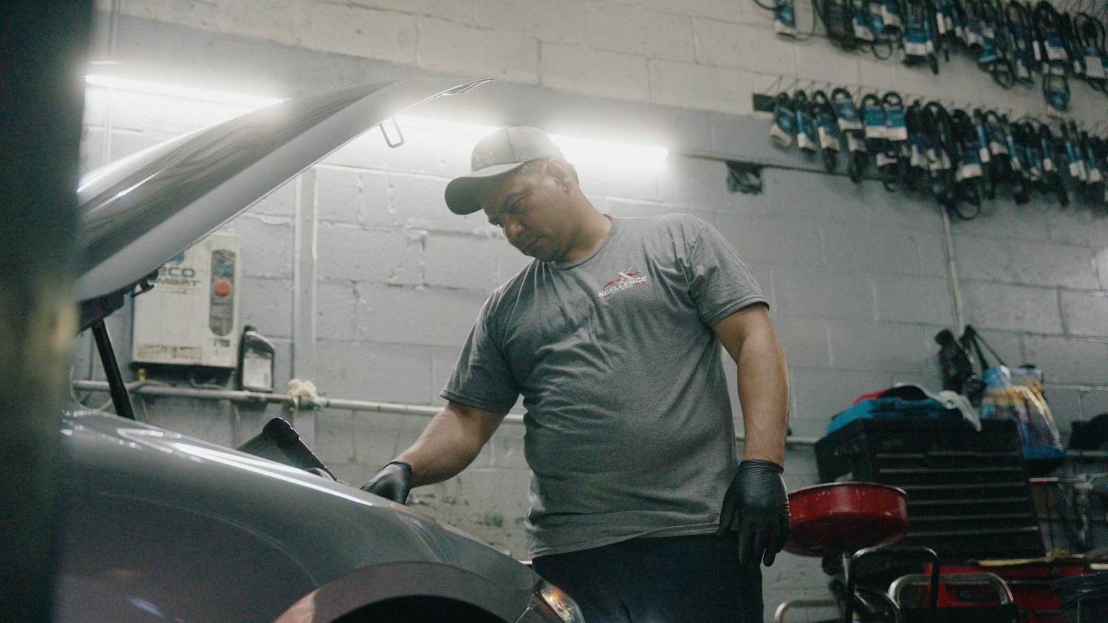 Excellence Auto Repair technician inspecting an engine under the hood